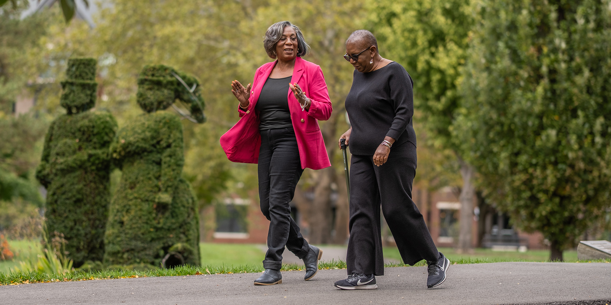 Ohio State community health worker Delores Richardson and cancer survivor Joyce Calamese walk in a park.