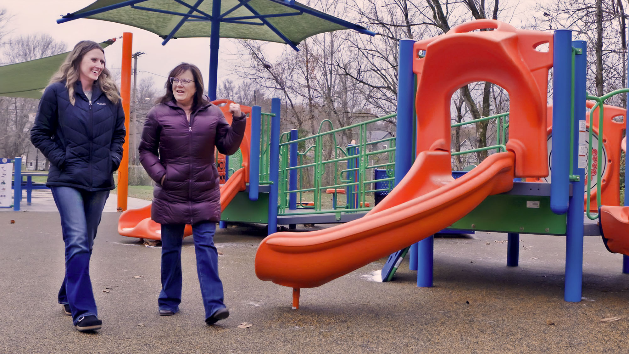 Two women walk across a playground