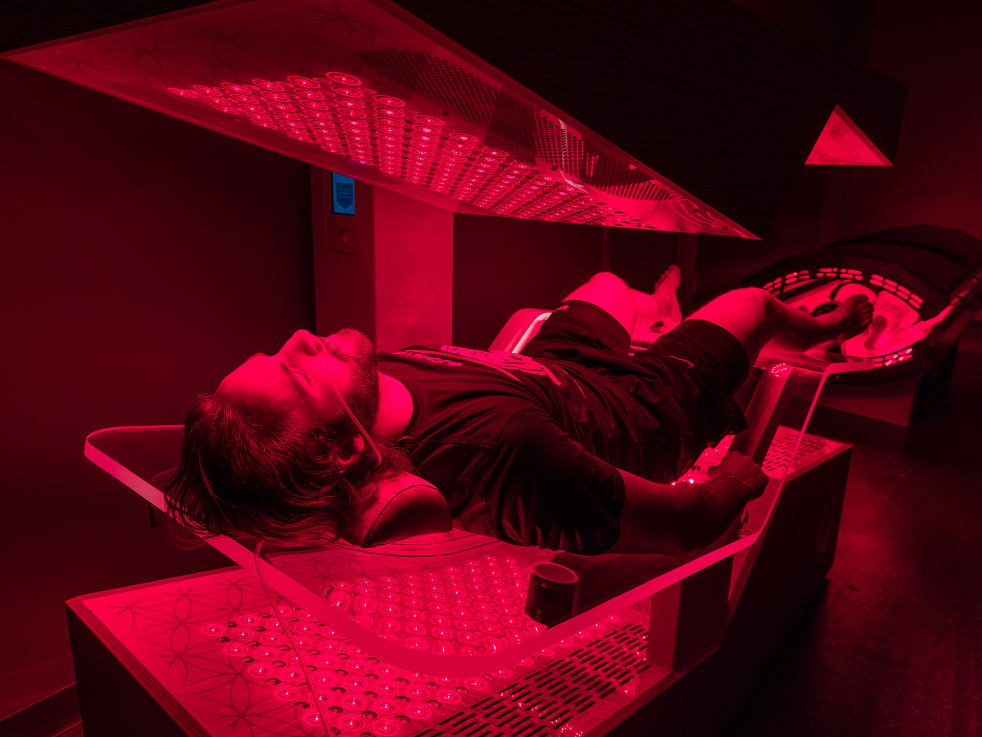 A student lays on a bed that helps regenerate injuries. There is a red hue over the photo.