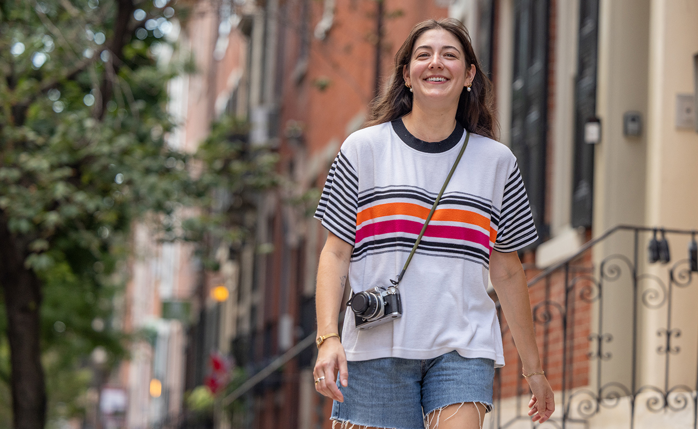A young woman walks down the street of an urban neighborhood