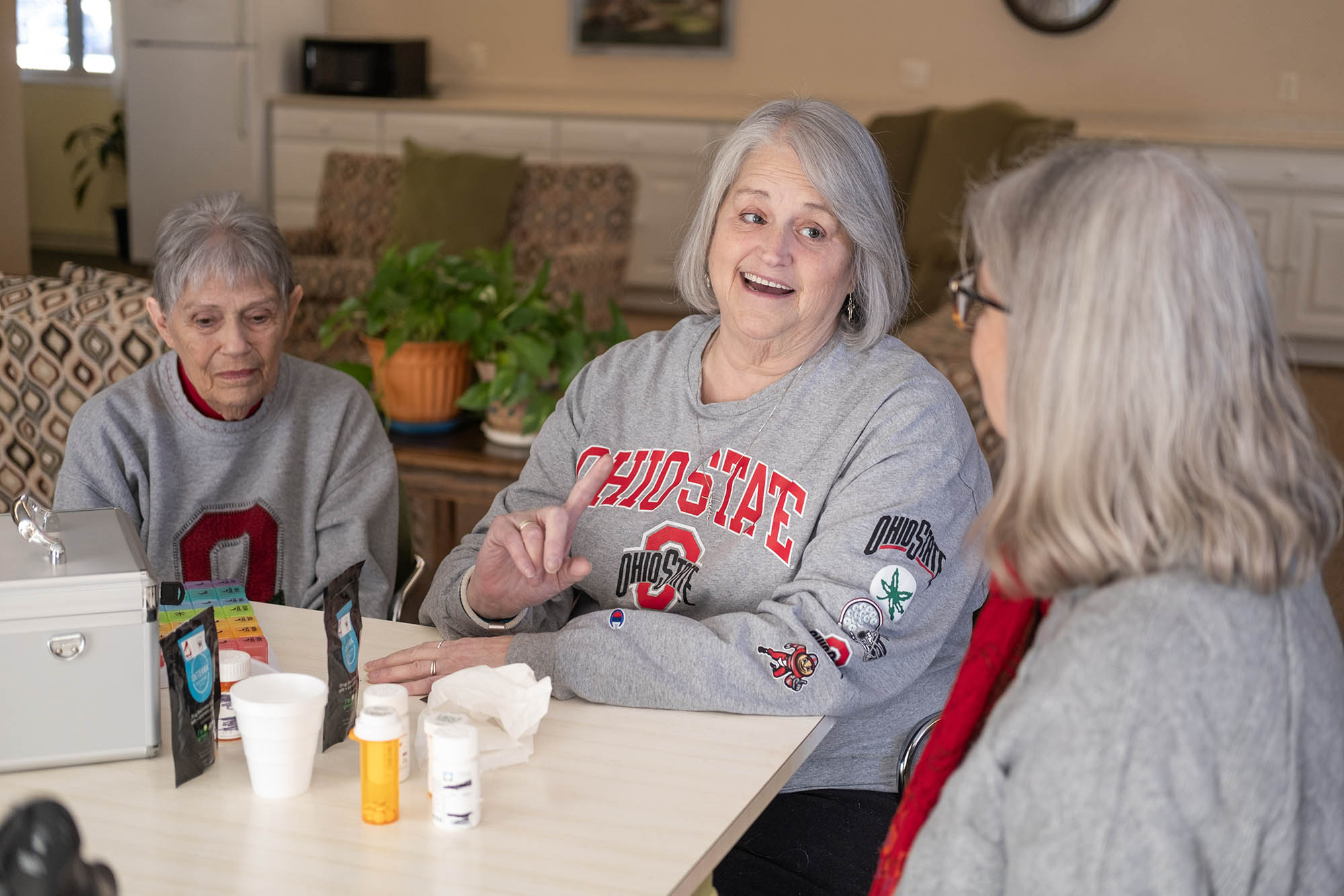 Three women sit at a table talking to one another.