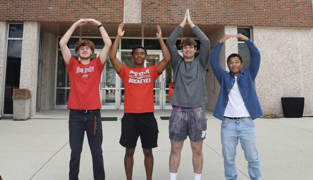 Four students do O-H-I-O on the Ohio State campus