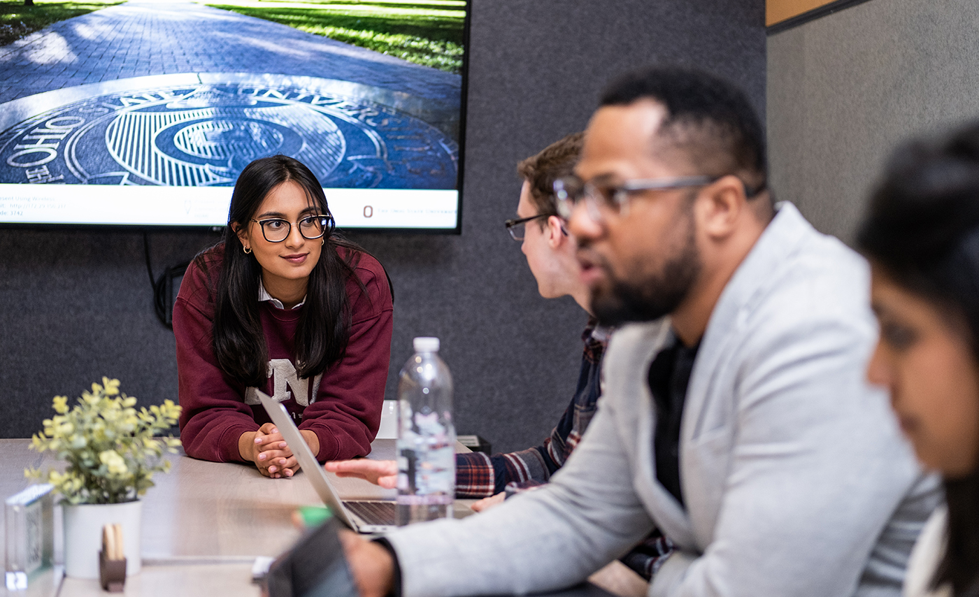 A group of student entrepreneurs sit at a table and discuss their plans.