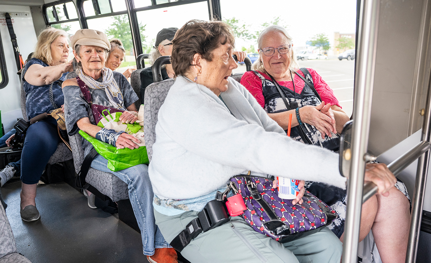 A group of older adults interact while sitting in the Mary-Go-Round assisted transportation shuttle.