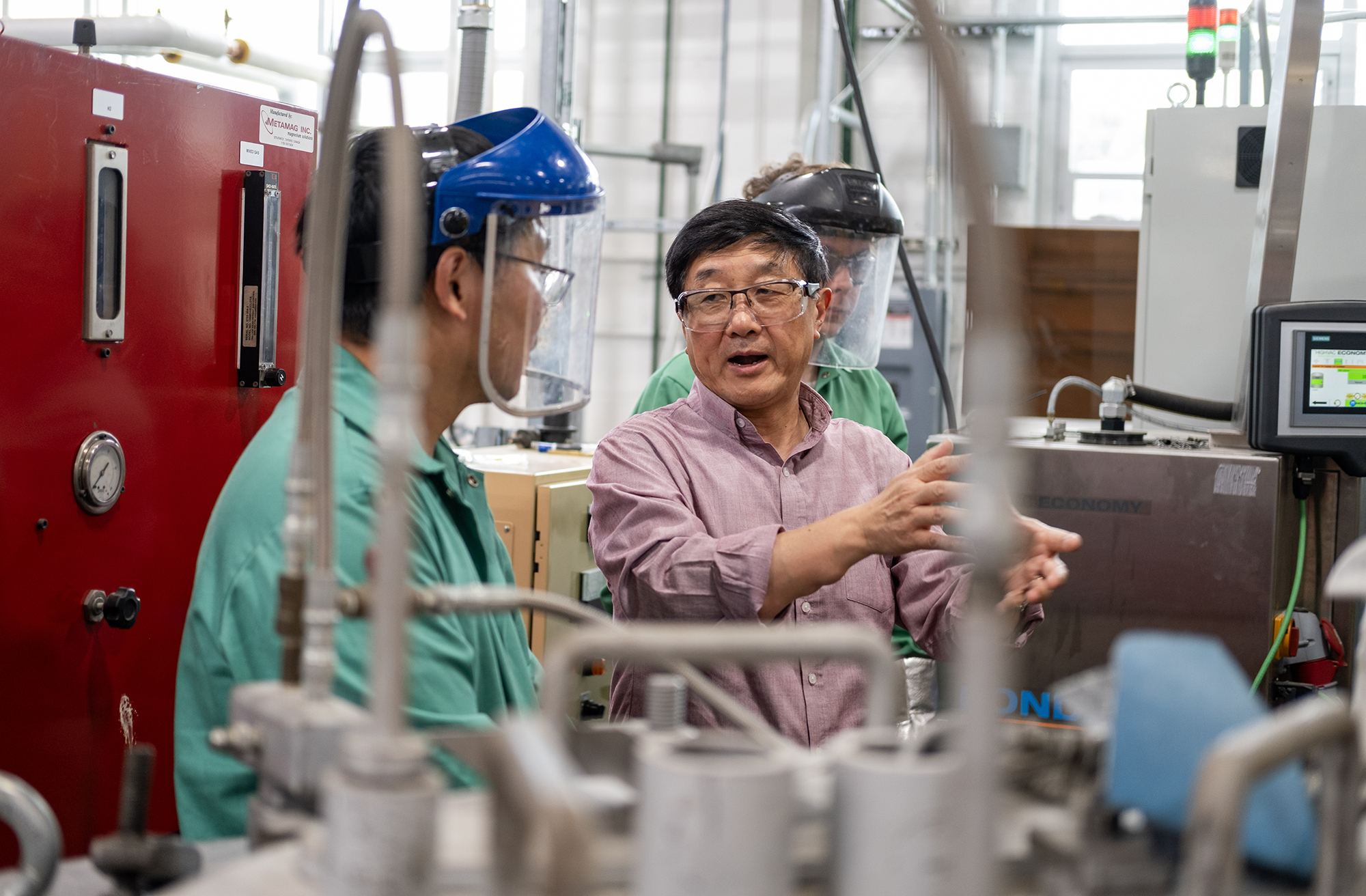 A scientist in a lab talks to a colleague with research material around him.
