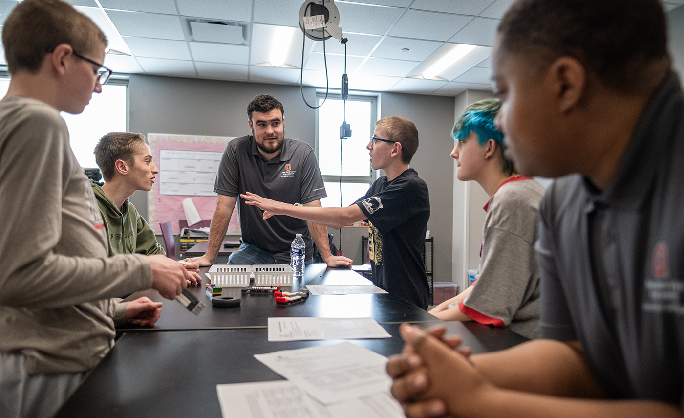 An instructor listens to questions from junior high students