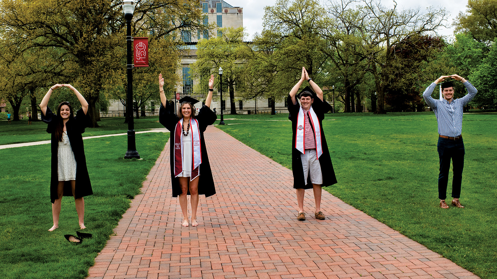 Four recent graduates pose as OHIO on campus