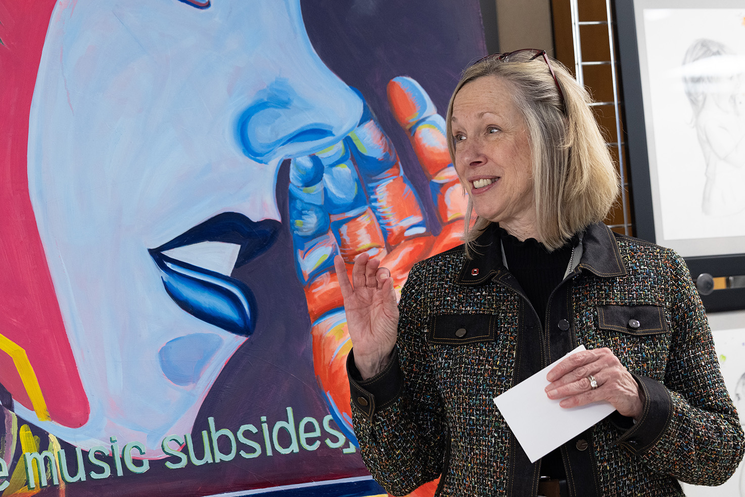 Carol Bradford, MD smiling while she talks, standing in front of colorful art