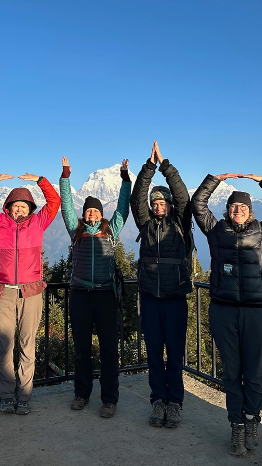 A group of four people spell OHIO in front of a beautiful mountain