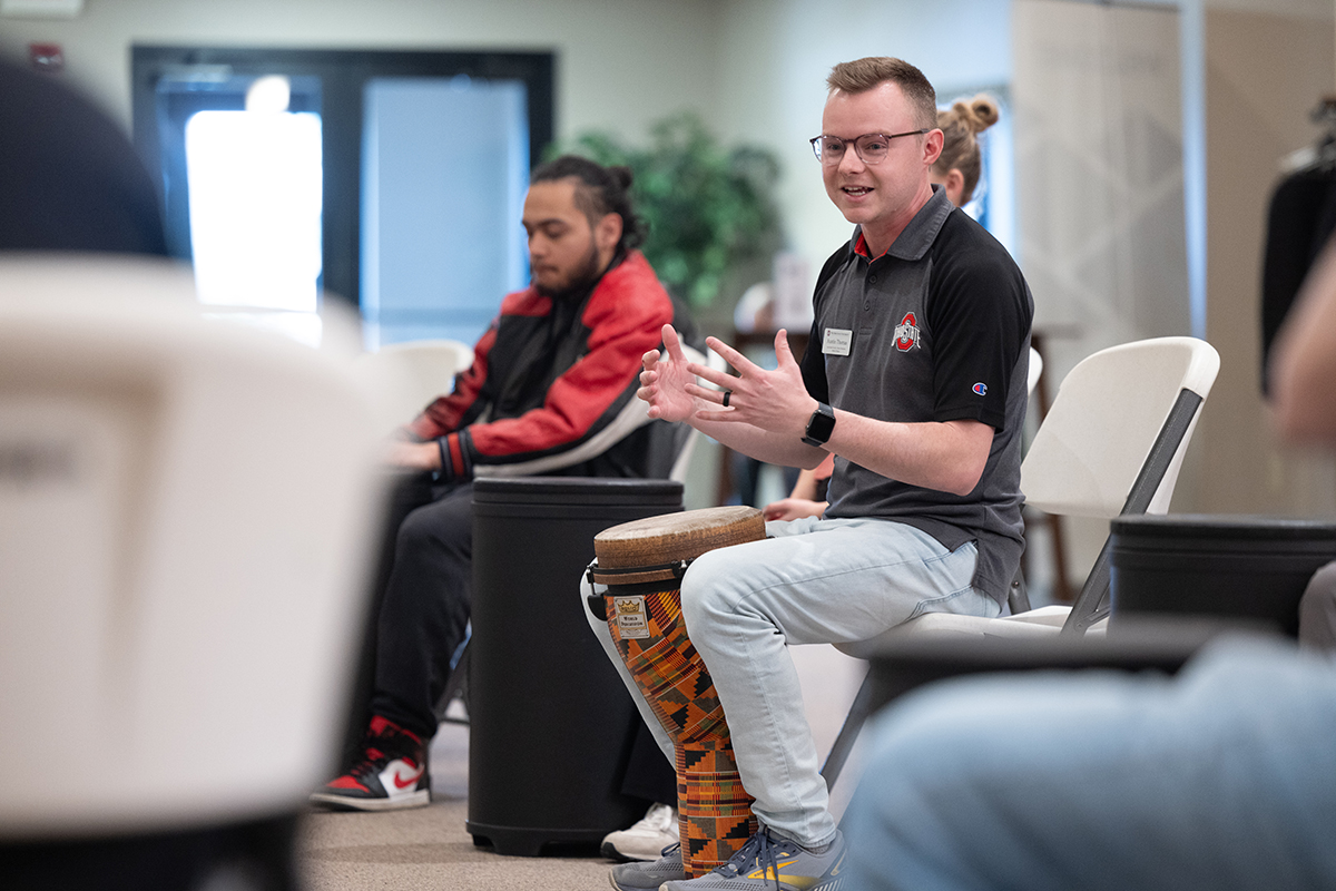 A man in an Ohio State shirt smiles as he talks to a colleague