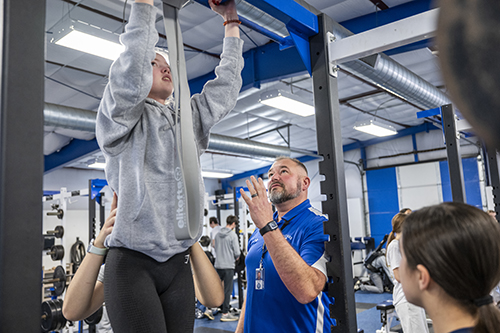 Hilliard Davidson girls track and field coach provides instruction for a girls student-athlete doing pull-ups
