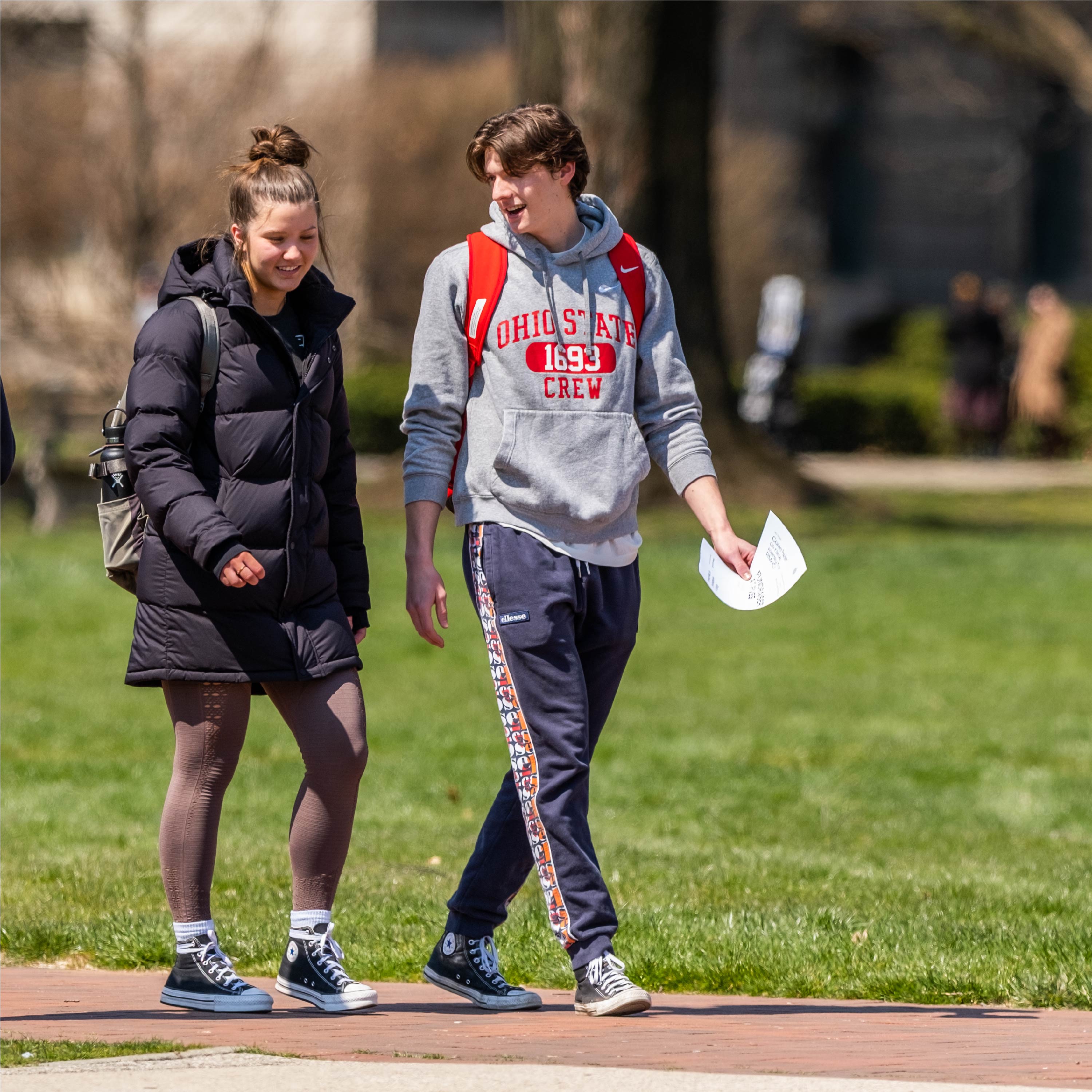 Two students walk across the Oval together.
