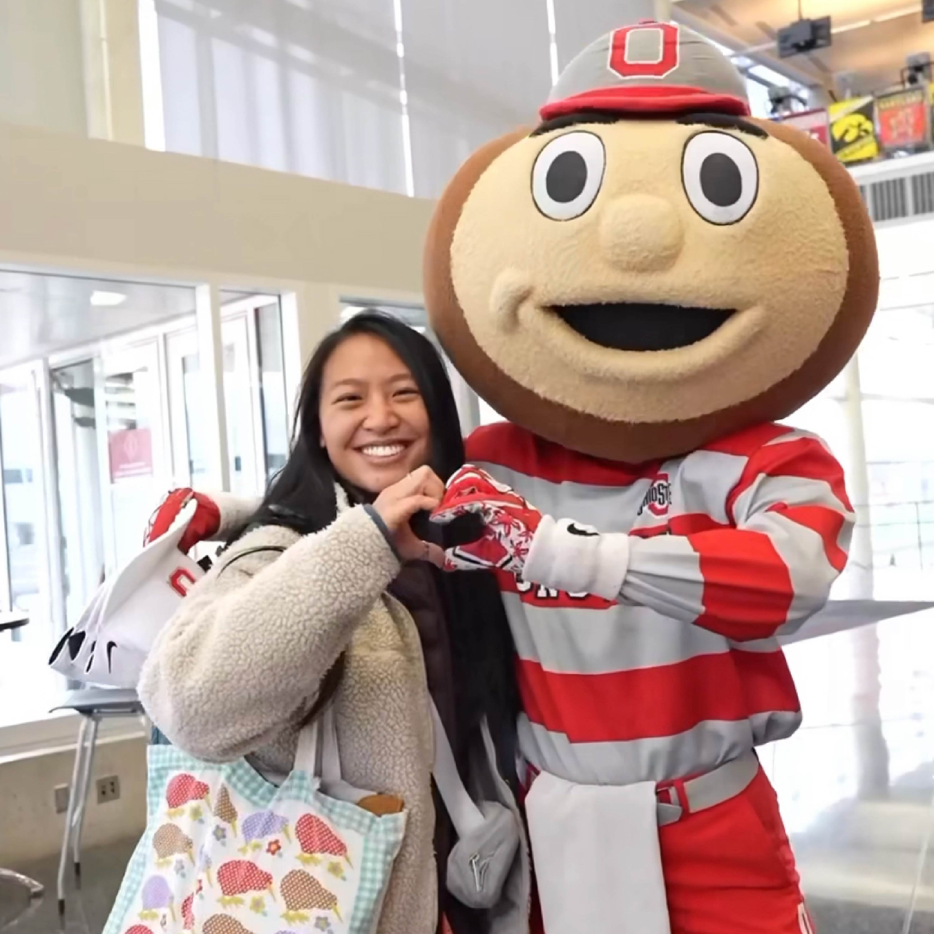 Brutus Buckeye and a friend join hands to make the "heart" symbol.