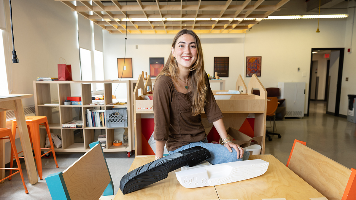 A student smiles at the camera while standing in an industrial design lab at Ohio State