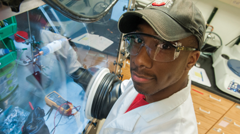 A student in a lab looks at the camera