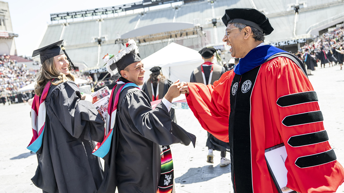 Ohio State president Ravi V. Bellamkonda shares a fist-bump with an Ohio State graduating student