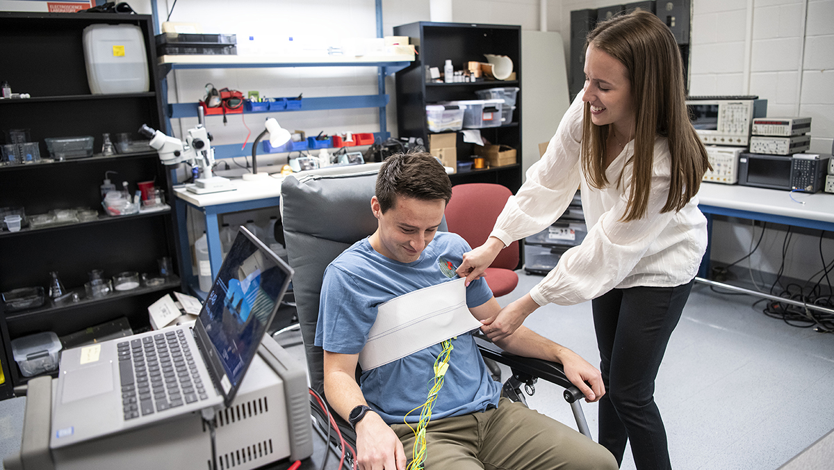 Ohio State student Ally Rice applies sensors to a student seated in a chair in a lab