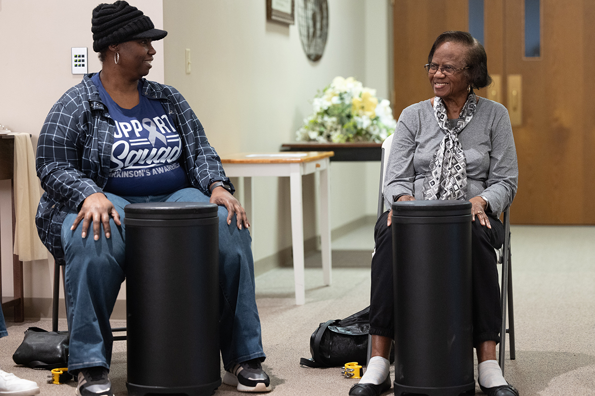Two women are seated with drums in front of them.
