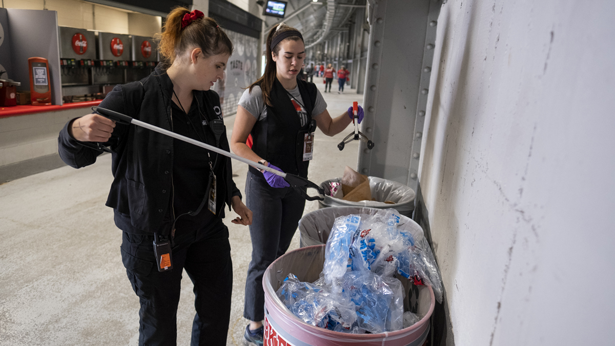 Two Ohio State students use calipers to remove waste from a garbage can at Ohio Stadium.Zero Waste interns Maya Hammond, left, and Lauren Monnin sort trash at Ohio Stadium on a fall game day.
