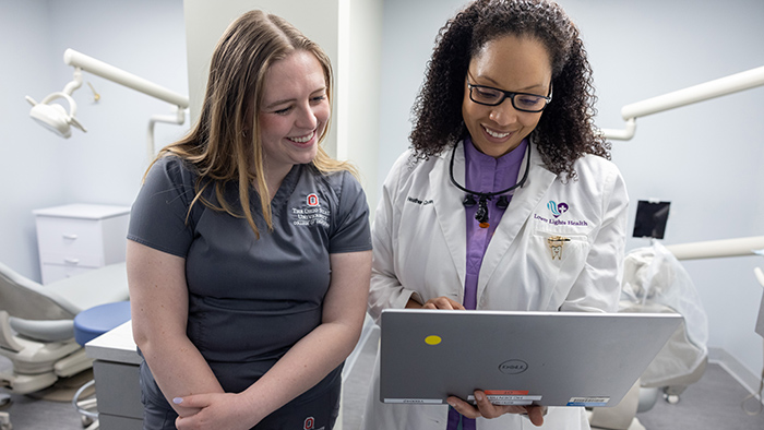 Dental associates smiling while looking at a laptop
