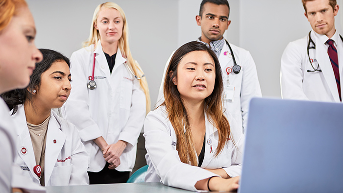 A group of medical professionals looking at a laptop