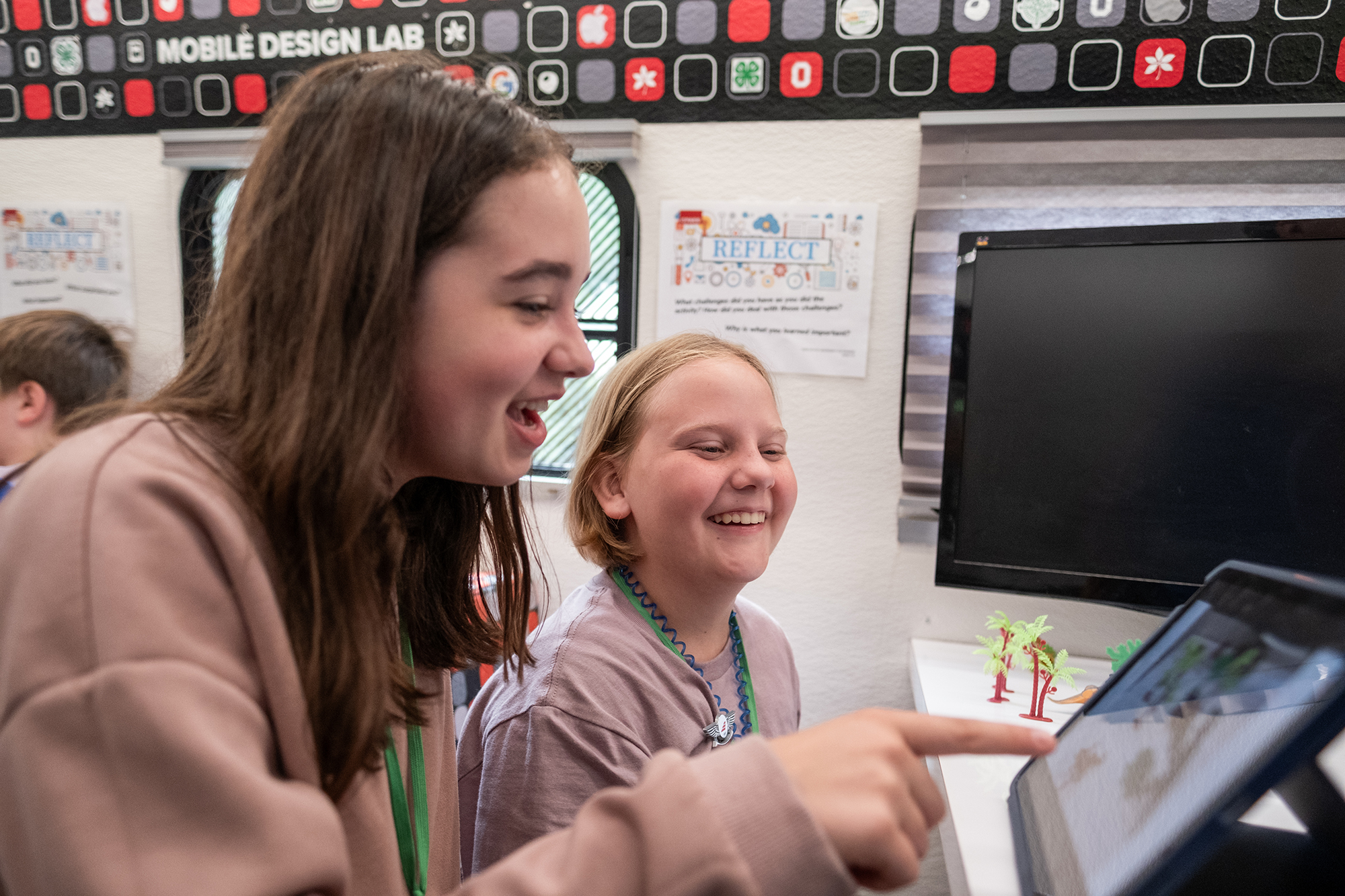 Two young people work on a tablet during a visit from the Mobile Design Classroom