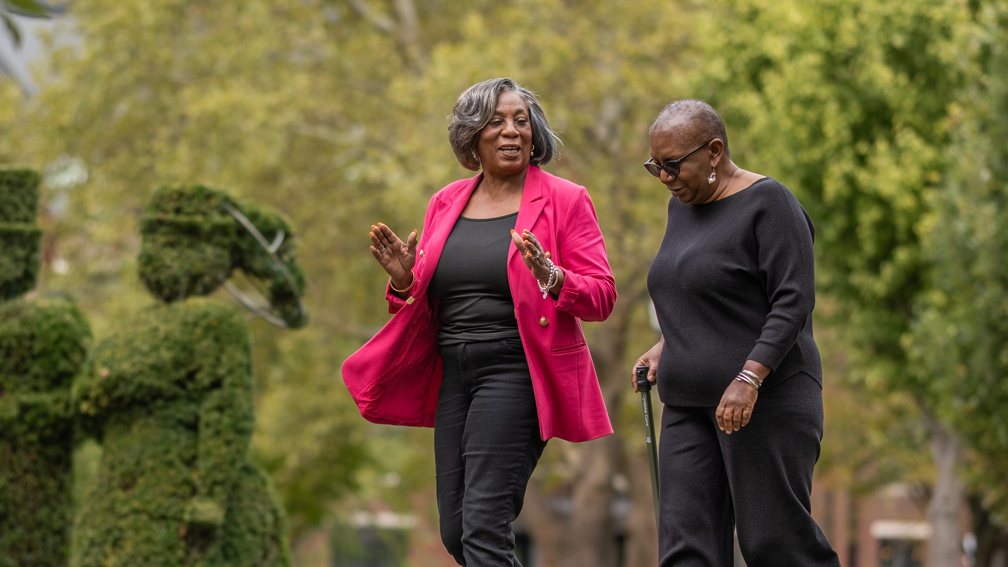 Ohio State community health worker Delores Richardson and cancer survivor Joyce Calamese walk in a park.