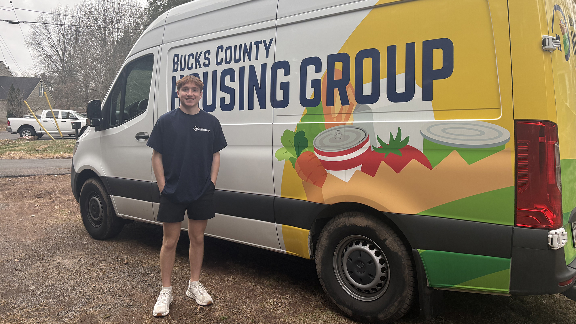 A student stands in front of a food delivery truck.