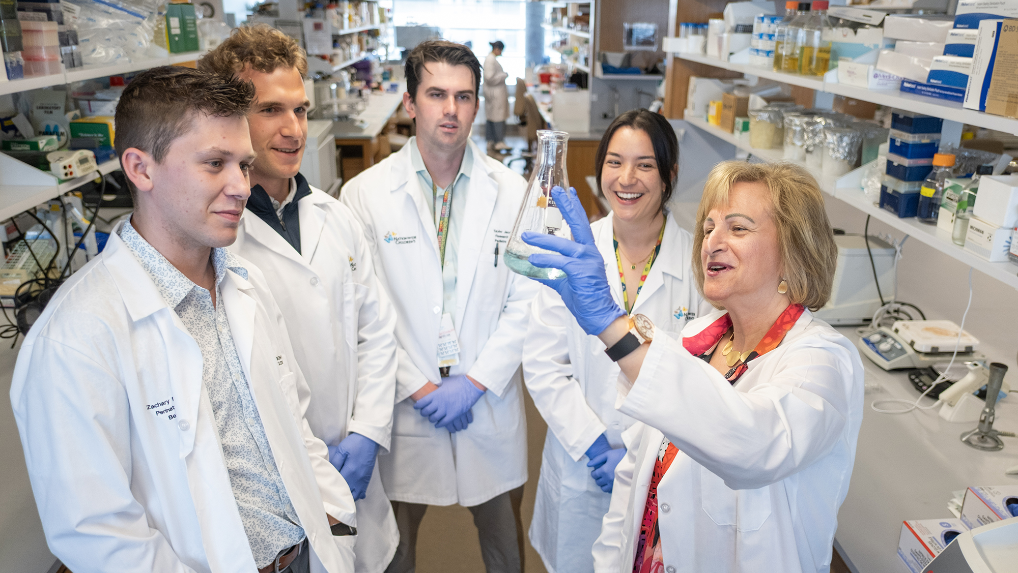A group of five researchers look together at a container of fluid