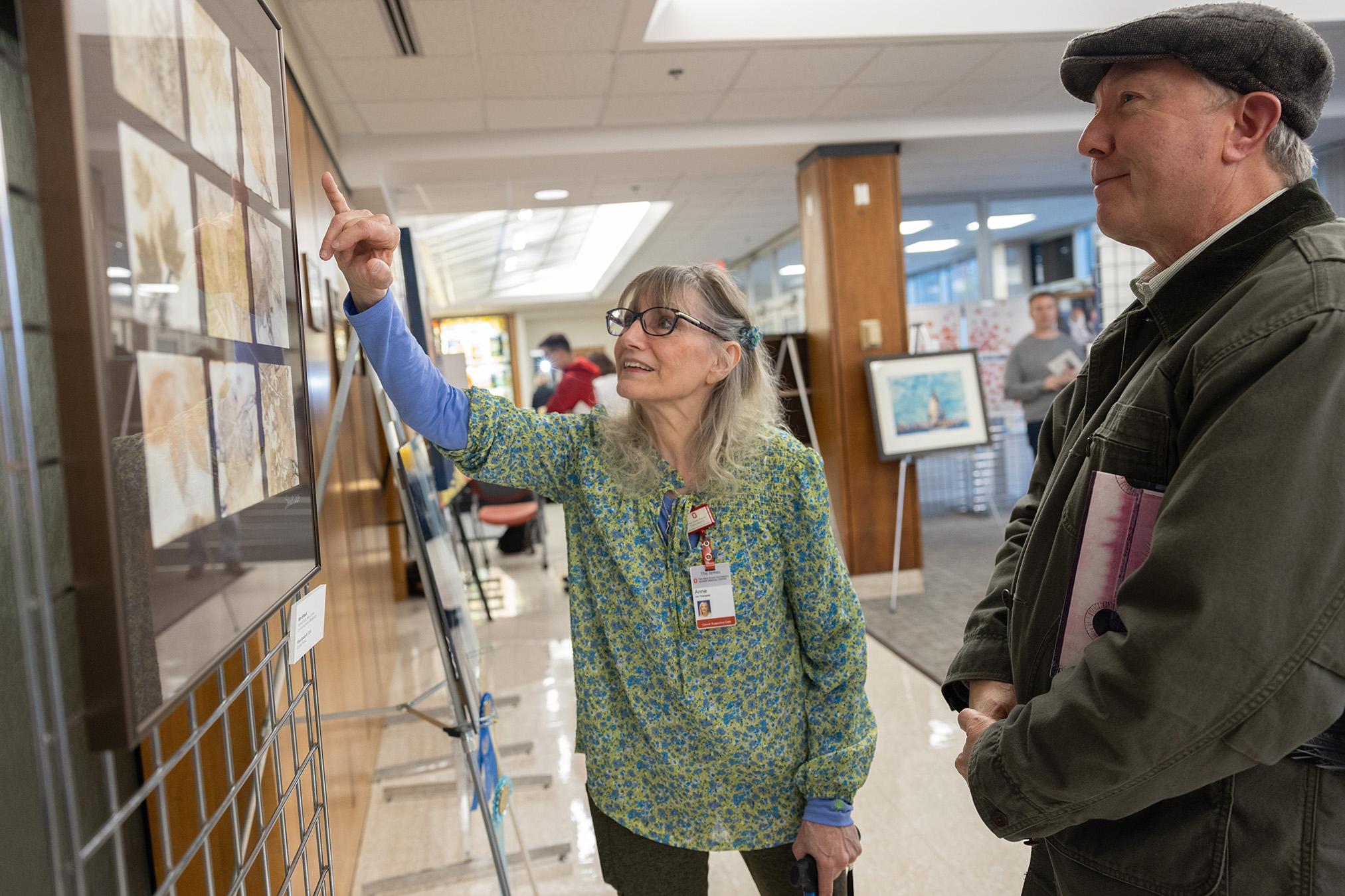 Women in green top pointing out a piece of art to a smiling man