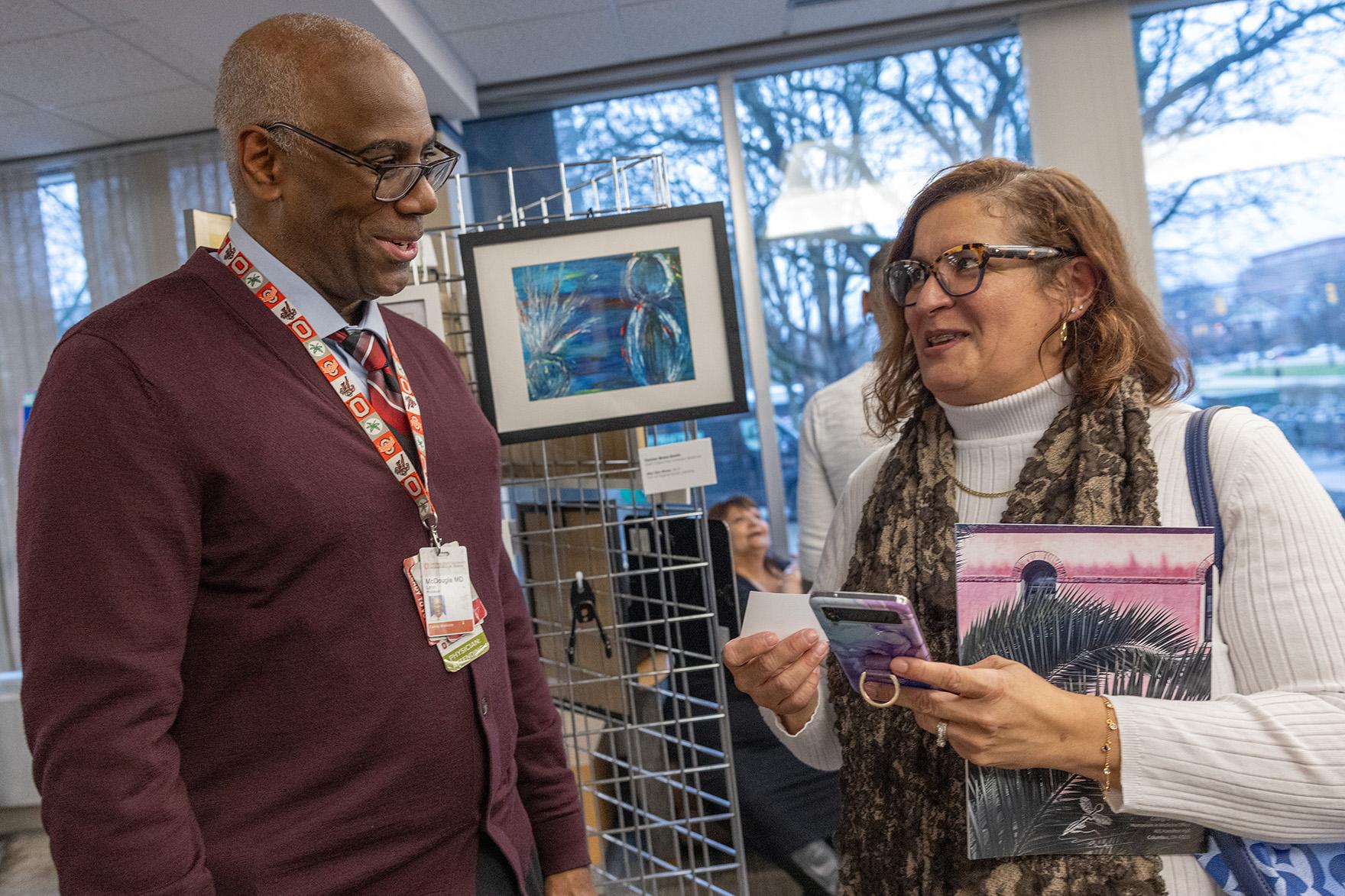 Man and woman talking while the woman holds a piece of tropical pink art