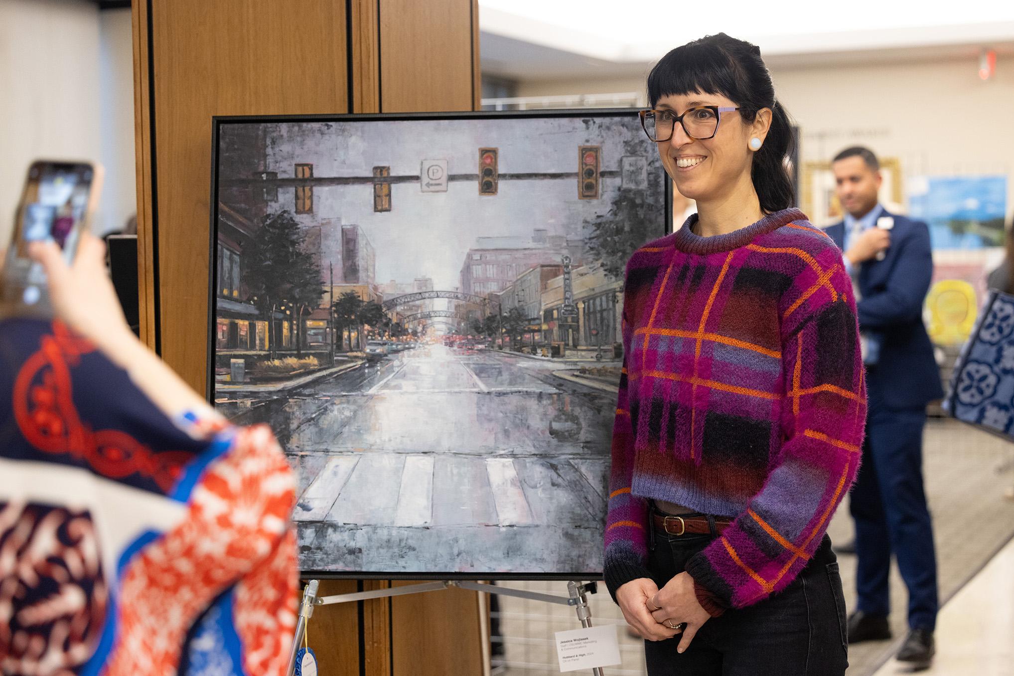 Smiling woman having her photo taken next to a large painting of a crosswalk