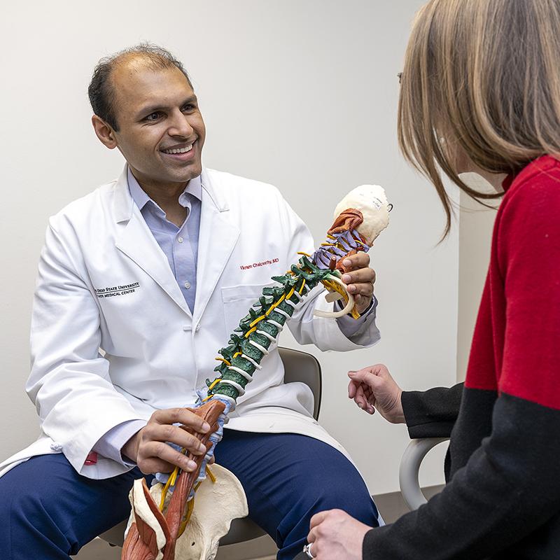 An Ohio State doctor holds the replica of a spine as he talked with a patient.