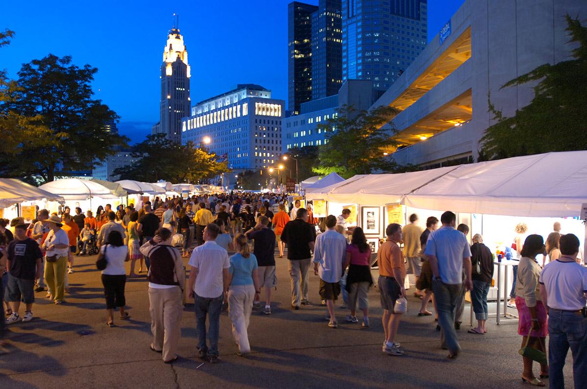 Crowd of people walking through Columbus Arts Festival with skyline in background