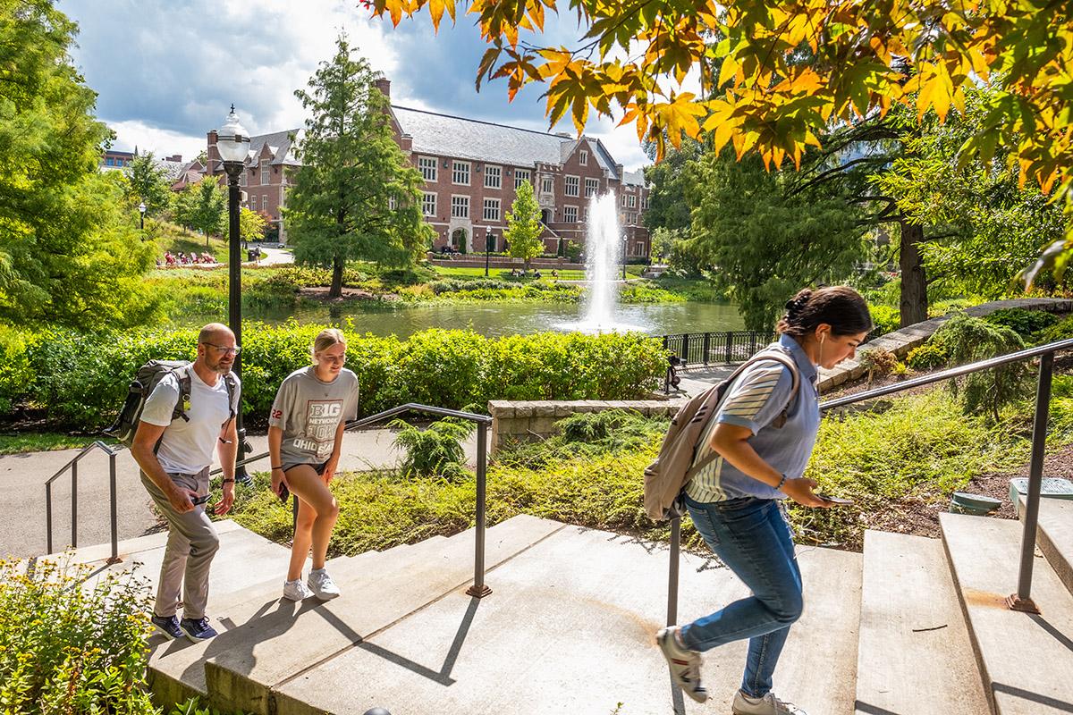 Three people walk up stairs near Mirror Lake