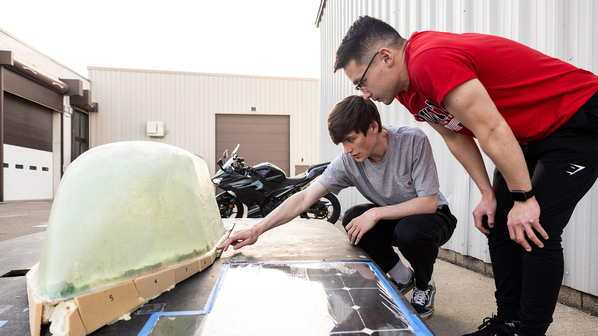Two students examining prototype solar powered vehicle
