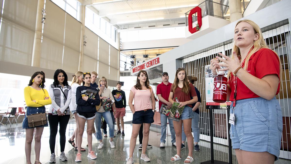 A student ambassador talks to a group of prospective students at a campus Welcome Center