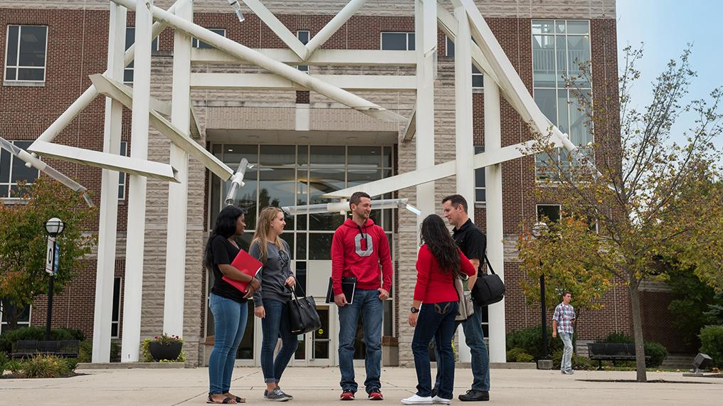 Students stand outside a building talking on the Lima campus