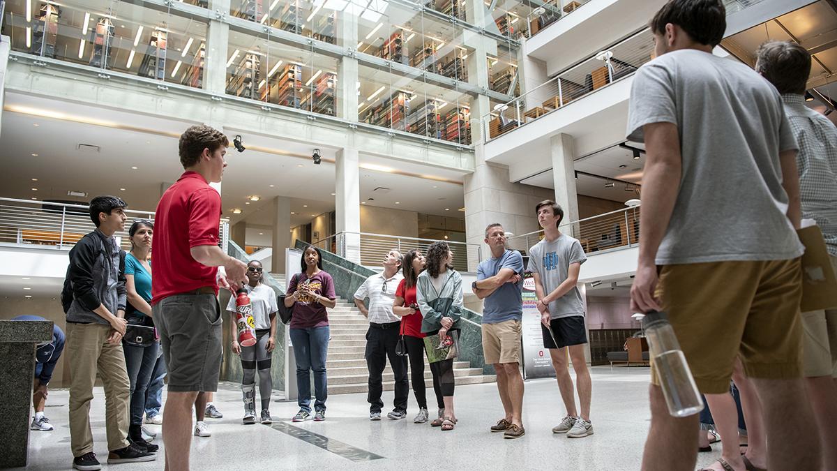 Students on a campus visit listen to a Buckeye ambassador in the lobby of the Thompson Library