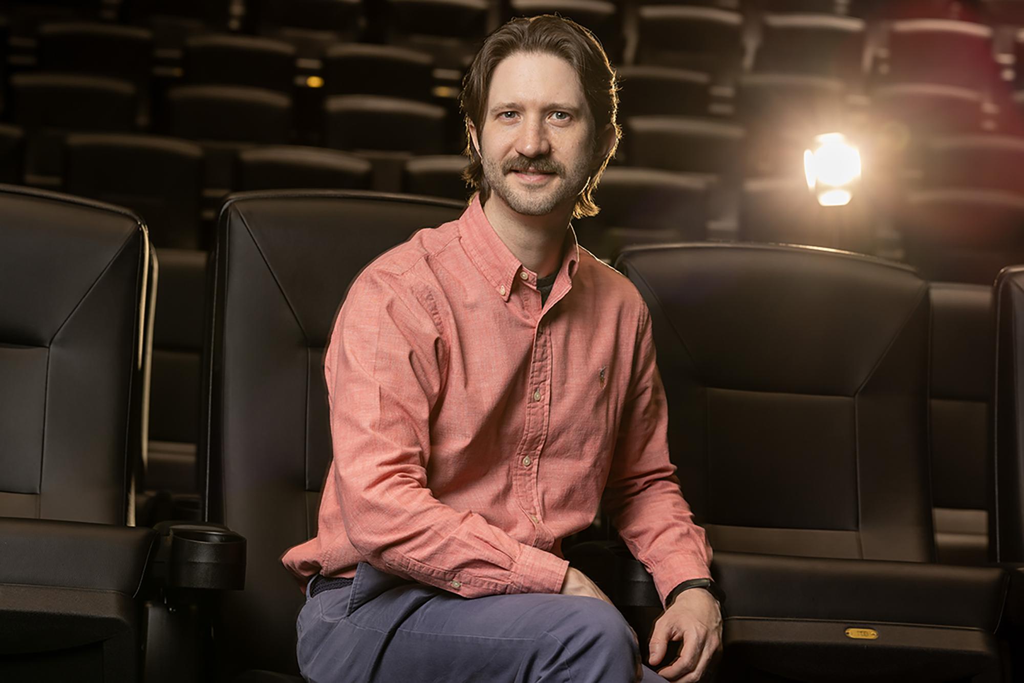 Ohio State School of Communication faculty Matt Grizzard poses for a portrait with a lit stage light over his right shoulder