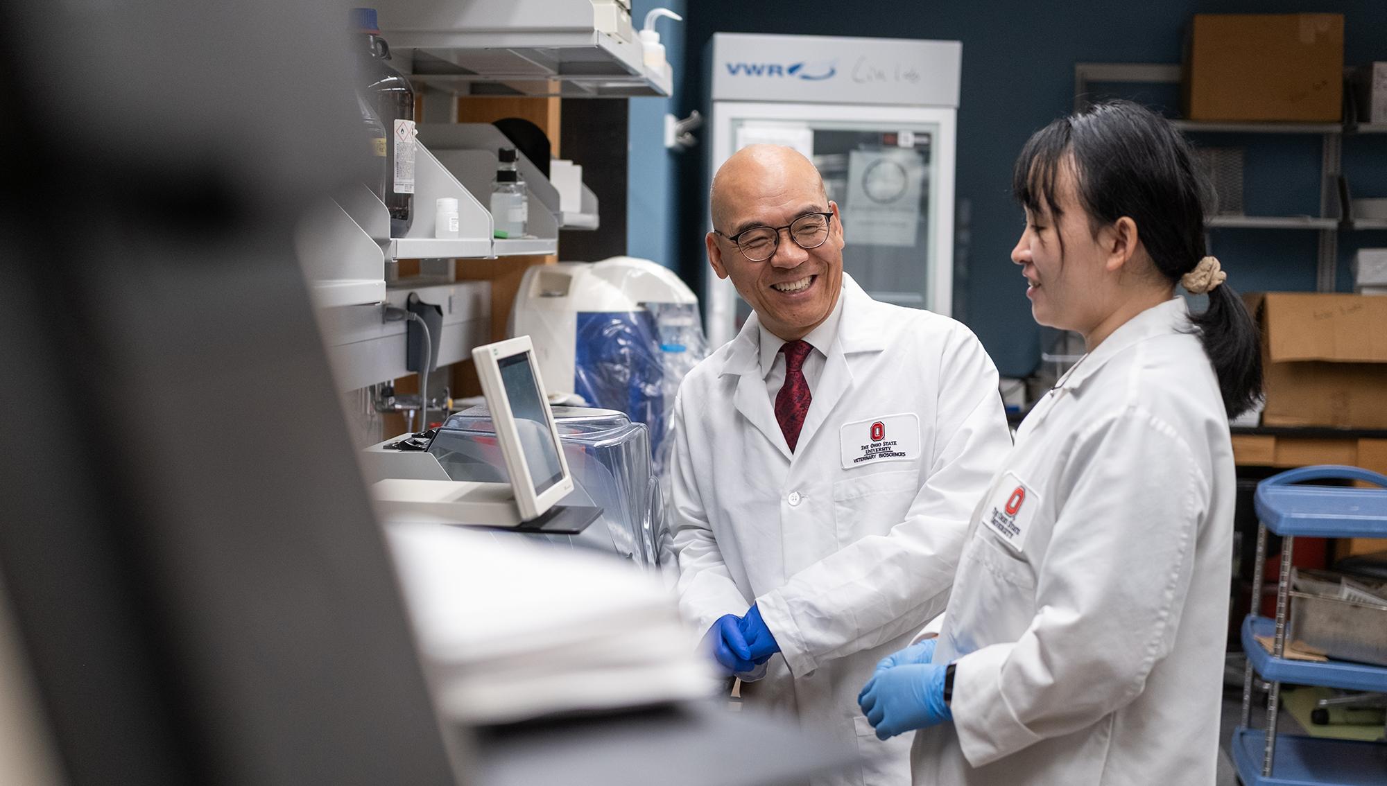 A researcher looks and smiles at a fellow researcher as they work on a project together.